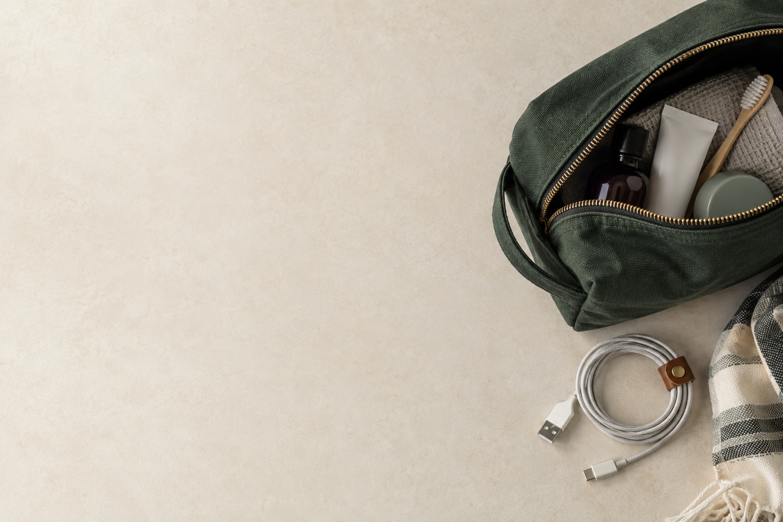 Travel pouch and charging cable on a warm paper surface